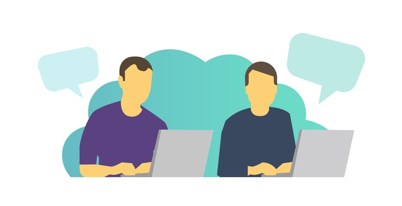 Two men work sitting at laptops and chatting